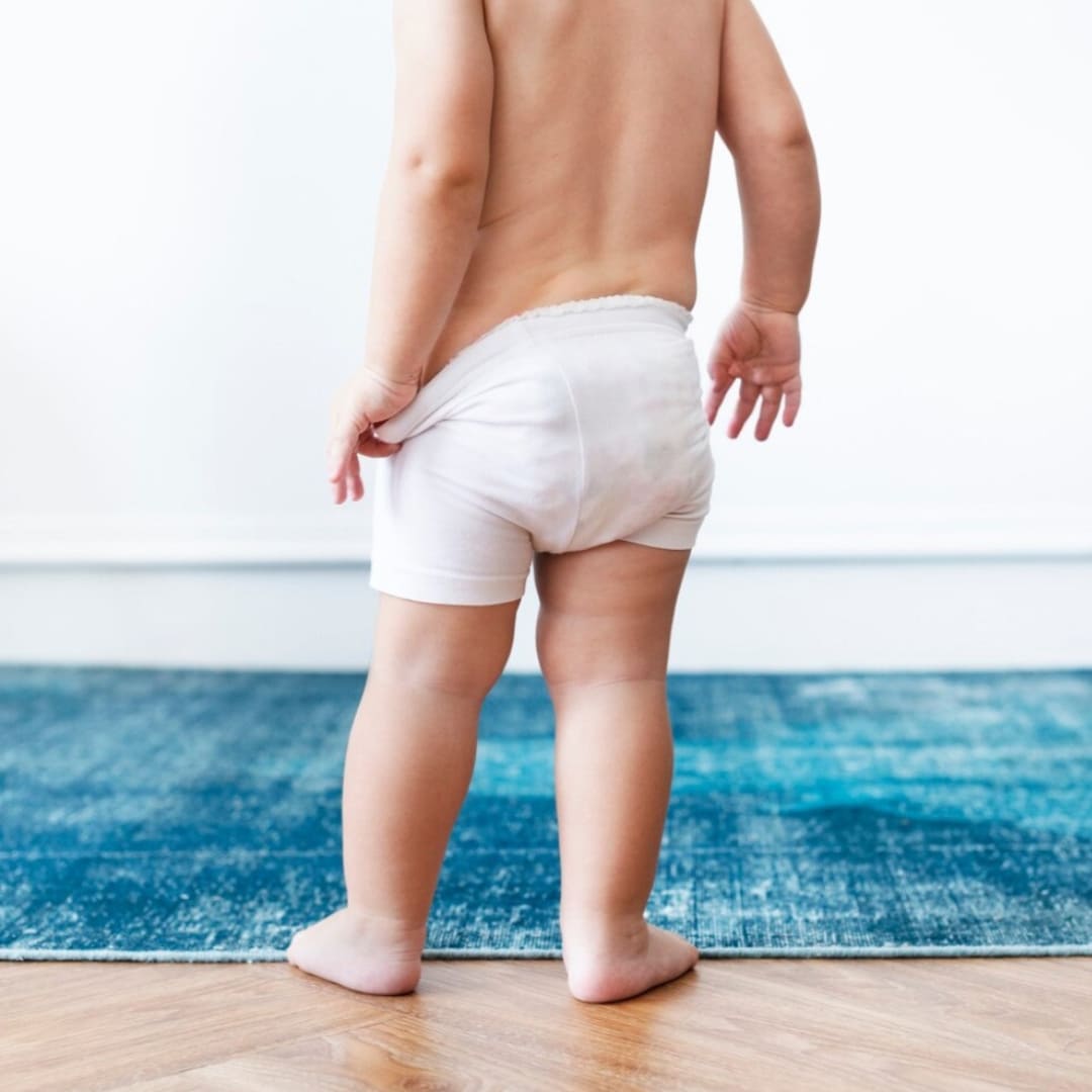 Bébé de dos portant une culotte d’apprentissage douce et respectueuse de la peau.
